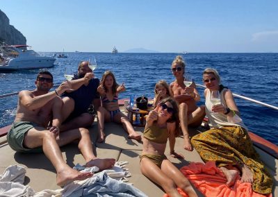 famiglie, amici, che brindano sulla poppa del gozzo a noleggio, a largo di Capri